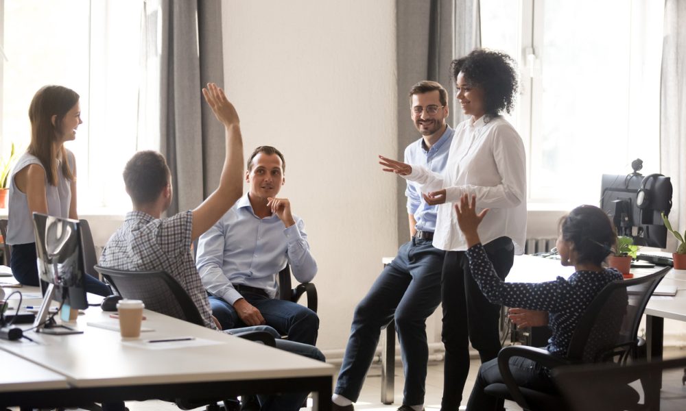 Diverse team in coworking space voting some colleagues agree raises hands. Positive black leader woman with creative group of businesspeople discussing sharing ideas together in office at meeting